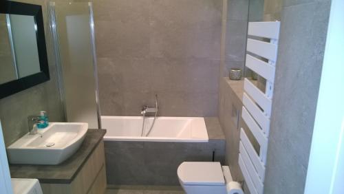 a bathroom with a tub and a toilet and a sink at Kavo Sopot Apartment in Sopot