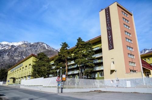 ein Gebäude auf einer Straße mit Bergen im Hintergrund in der Unterkunft Villaggio Olimpico in Bardonecchia