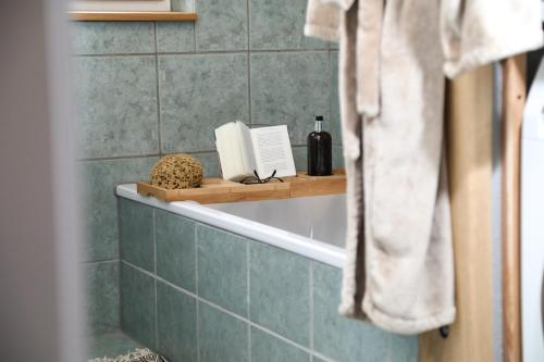 a bathroom with a bath tub with a book on a shelf at Marhold Apartments in Drensteinfurt