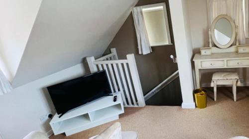 a living room with a tv and a staircase with a mirror at Laverick Steps in Whitby