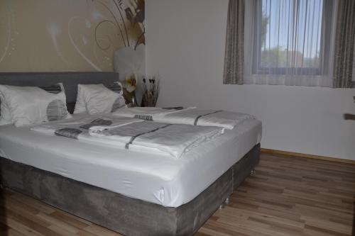 ein großes Bett in einem Schlafzimmer mit weißer Bettwäsche in der Unterkunft Bungalow Serajnik in Sankt Kanzian am Klopeiner See