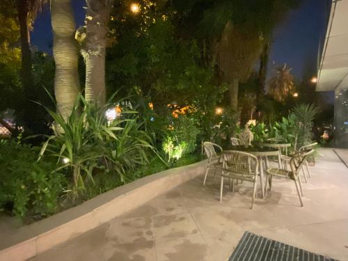 a patio with tables and chairs and plants at night at Mansouri Mansions Hotel in Manama