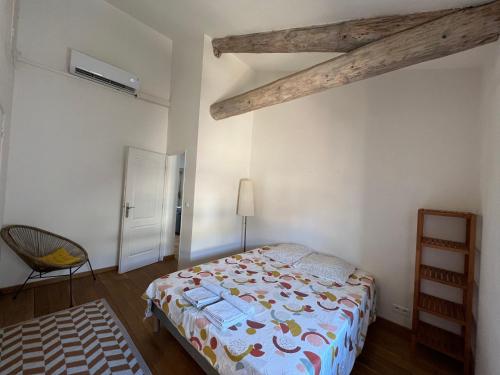 ein Schlafzimmer mit einem Bett und einem Stuhl darin in der Unterkunft Nimes centre ville appartement cosy 2 chambres in Nîmes