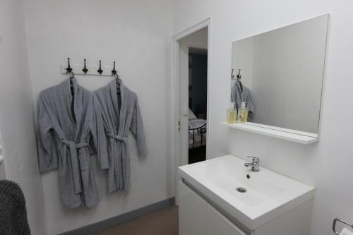 W białej łazience znajduje się umywalka i lustro. w obiekcie La Charentaise des Lilas w mieście Saint-Léger