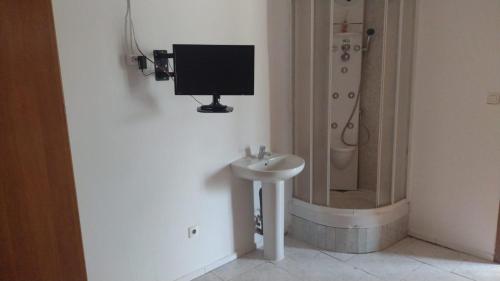a bathroom with a sink and a shower with a television on the wall at albergue bar villamayor in Villamayor del Río