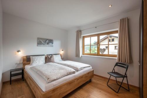 1 dormitorio con 1 cama, 1 silla y 1 ventana en Haus Klingenschmid en Hopfgarten im Brixental