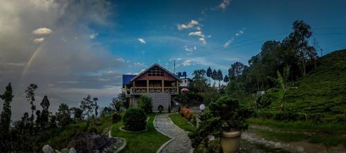 a house on a hill with a rainbow in the sky at Vamoose Manali Beach Resort in Bhogwe