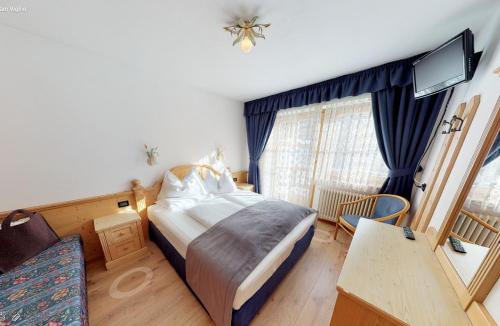 a bedroom with a bed and a desk and a tv at Villa Ortensia in San Vigilio Di Marebbe