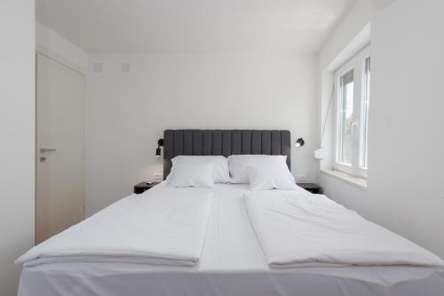 a large white bed in a white room with a window at Apartman Noa in Kastav