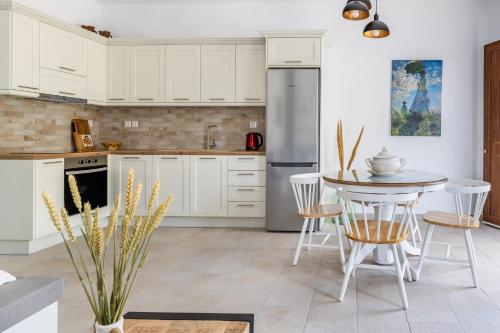 cocina con armarios blancos, mesa y sillas en Stafylos Green, en Skopelos Town