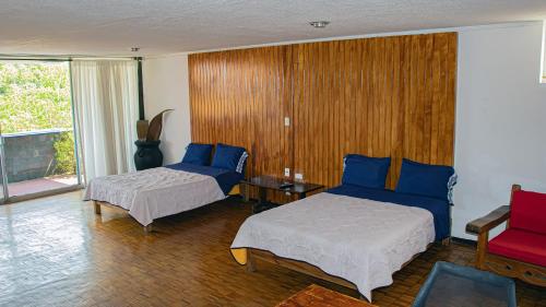 Suites Las Plazas في كويرنافاكا: غرفة نوم بسريرين واريكة وطاولة