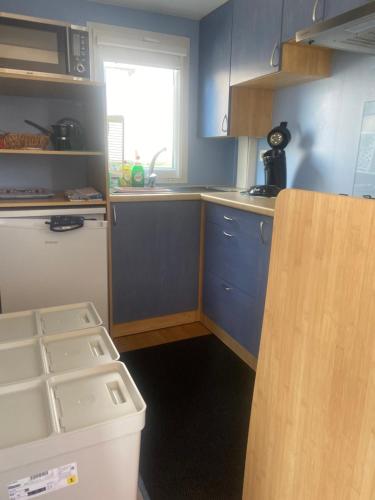 eine kleine Küche mit blauen Schränken und einem Fenster in der Unterkunft Chalet Sonnenschein in Bredene