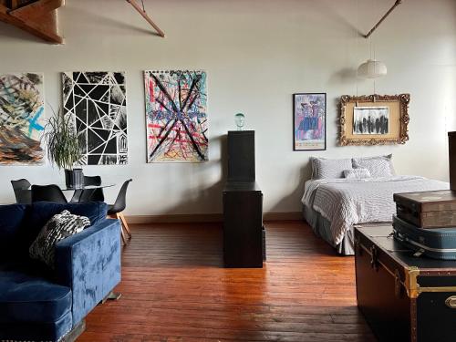 a living room with a bed and paintings on the wall at 420 Friendly Loft Skyline/Canada View Free Parking in Detroit