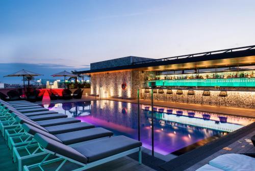 a swimming pool with lounge chairs next to a building at Catalonia Barcelona Plaza in Barcelona