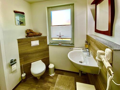 La salle de bains est pourvue d'un lavabo, de toilettes et d'une fenêtre. dans l'établissement Gemütliche Ferienwohnung, à Sagard