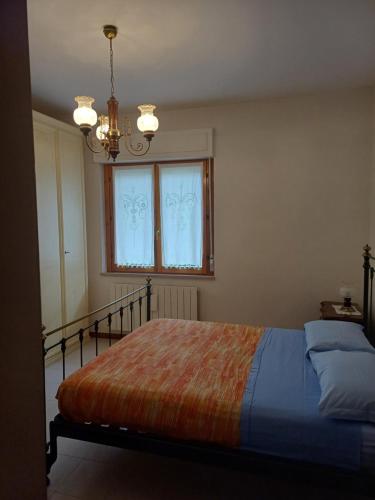 - une chambre avec un lit, une fenêtre et un lustre dans l'établissement La terrazza, à Tuoro sul Trasimeno