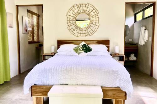 a bedroom with a large white bed and a mirror at Sharma Costa Rica - Heliconia Casita in Uvita