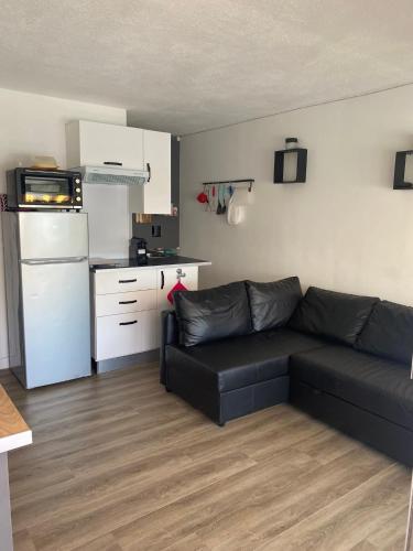 un salon avec un canapé noir et une cuisine dans l'établissement Appartement Vue mer Port Santa Lucia, à Saint-Raphaël