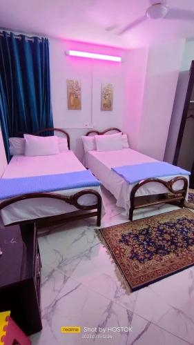 two beds in a room with pink lighting at Porto said in Port Said