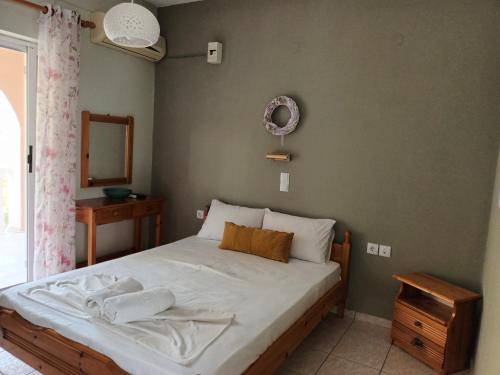 een slaapkamer met een bed met witte lakens en een spiegel bij Oasis in Amoudi