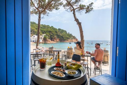 a table with food on it with a view of the ocean at Hotel Hostalillo by Escampa Hotels in Tamariu