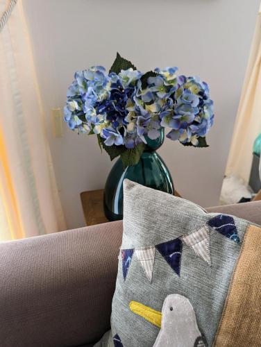 a vase with blue flowers and a pillow on a couch at Stylish Garden Apartment at Paphos Harbour in Paphos City