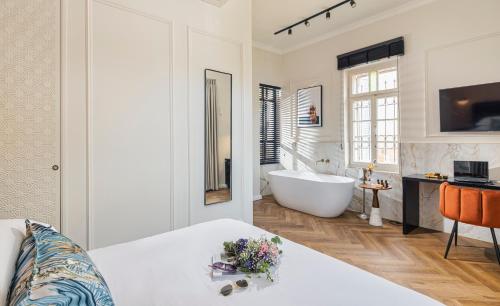 a white bathroom with a tub and a sink at Damson - Machne Yehuda Hotel in Jerusalem