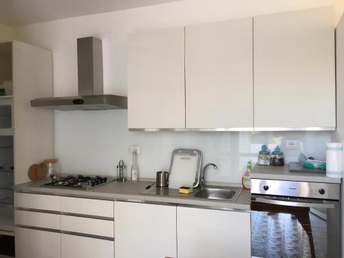 a white kitchen with white cabinets and a sink at L'Isolana Case Vacanza Villa Alessia in Ponza