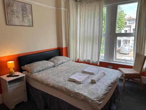 a bedroom with a bed with two towels and a window at Malvern Lodge Guest House- Close to Beach, Train Station & Southend Airport in Southend-on-Sea