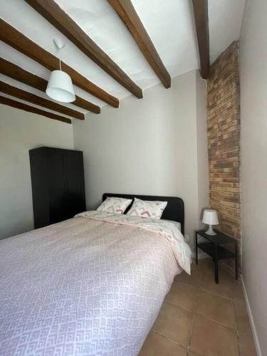 een slaapkamer met een bed en een bakstenen muur bij Charmante maison à la campagne in Sainte-Fauste