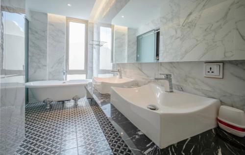 Baño blanco con 2 lavabos, bañera y tubermott en Feliz Hotel Binh Duong, en Thu Dau Mot