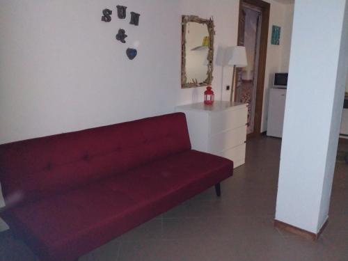 a red couch in a living room with a mirror at La Casa di Cri al Mare in Borgio Verezzi