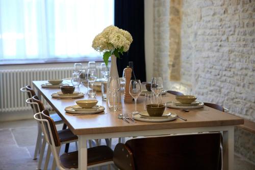a table with glasses and a vase of flowers on it at Couette&Living - Maison design à Savigny-les-Beaune in Savigny-lès-Beaune