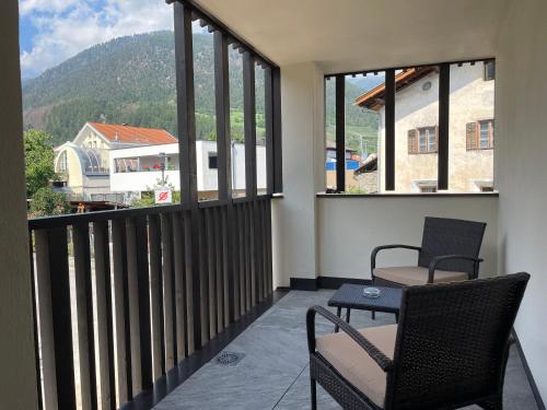 a balcony with two chairs and a table and windows at Pension & Residence Astoria in Prato allo Stelvio