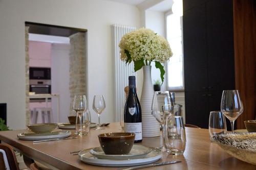 a dining room table with a bottle of wine and glasses at Couette&Living - Maison design à Savigny-les-Beaune in Savigny-lès-Beaune