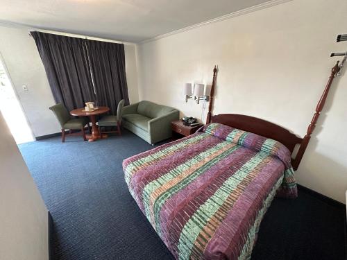 a hotel room with a bed and a chair at Four Oaks Lodging in Smithfield