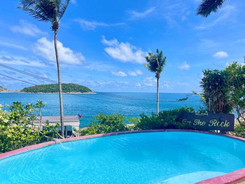a swimming pool with the ocean in the background at Naiharn On The Rock Resort Phuket in Nai Harn Beach