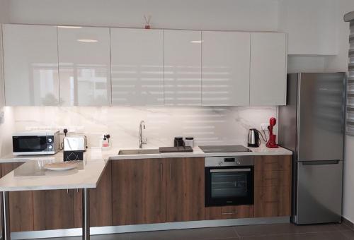 eine Küche mit weißen Geräten und Holzschränken in der Unterkunft New Smart Living-1 Bedroom Aglantzia, Nicosia in Aglantzia