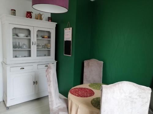 サン・ポル・ド・レオンにあるTy Pempoul - logement 2 chambres - 100 m de la plageのテーブルと白いキャビネットのある緑の部屋