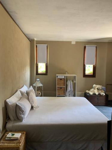 ein großes weißes Bett in einem Zimmer mit zwei Fenstern in der Unterkunft Il Riccio appartamento in Cernobbio