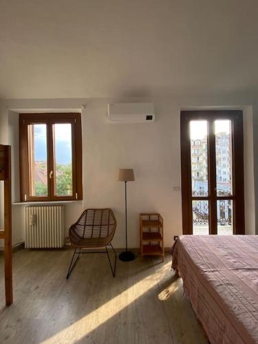 a bedroom with a bed and a chair and windows at La Casa di Nora in Turin