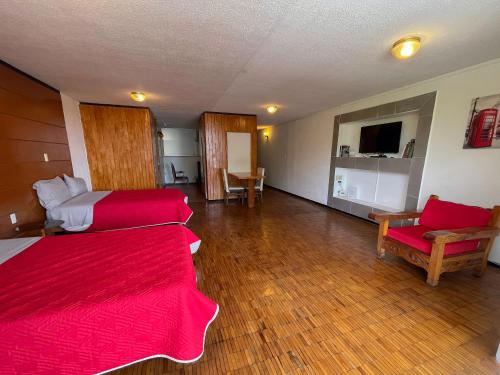 a room with two beds and a couch and a television at Suites Las Plazas in Cuernavaca