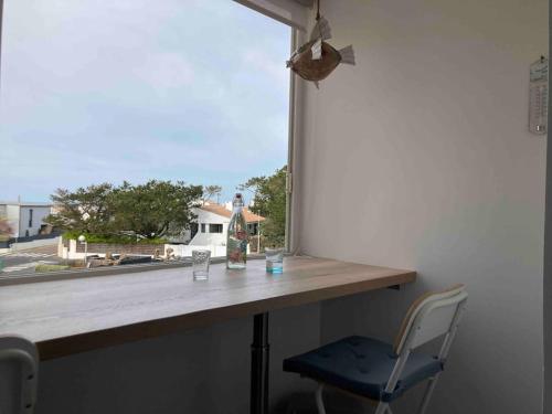 une table avec une chaise en face d'une fenêtre dans l'établissement Appart T2 av Loggia La Pironniere, à Les Sables-dʼOlonne