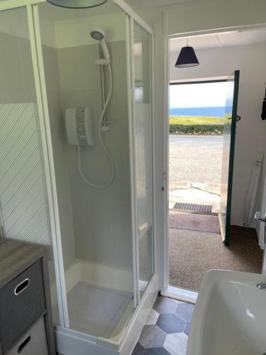 a bathroom with a shower and a sink and a toilet at Anne’s Thatched Cottage in Kilcar