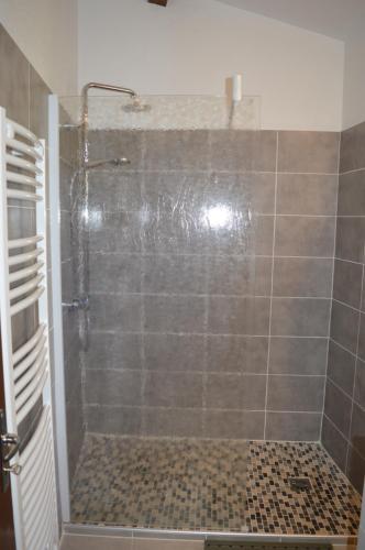 een badkamer met een douche en een glazen deur bij le moulin in Vallon-Pont-dʼArc