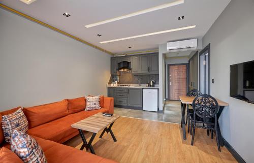 a living room with an orange couch and a kitchen at Sofyapart in Soğuksu