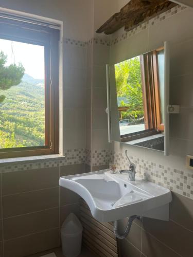 baño con lavabo, espejo y ventana en Green Deluxe Apartment “La locanda del Borgo”, en San Donato di Ninea