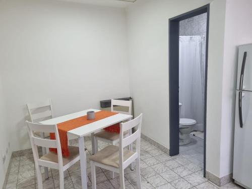a kitchen with a white table and chairs and a refrigerator at Hermoso departamento con patio en Rio Gallegos in Río Gallegos