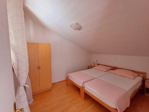 a bedroom with a bed with pink pillows at Apartman Mihaela in Komiža
