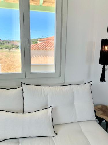 a white couch with pillows in front of a window at Syboro in Aloïziánika